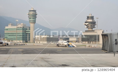 Hong Kong, China - 12th July 2025 - This is Hong Kong airport with ATC tower and a Cathay Pacific aeroplane. 128965404