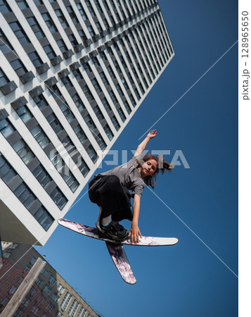Girl practices skiing tricks on a trampoline. Girl practices skiing tricks on a trampoline. 128965650
