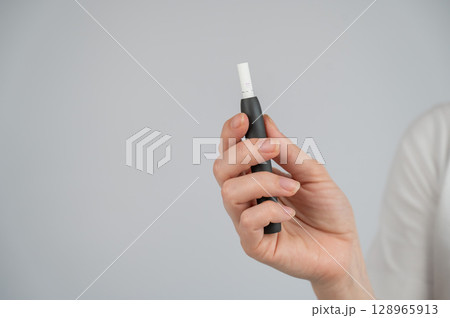Faceless woman holding tobacco heating system.  128965913