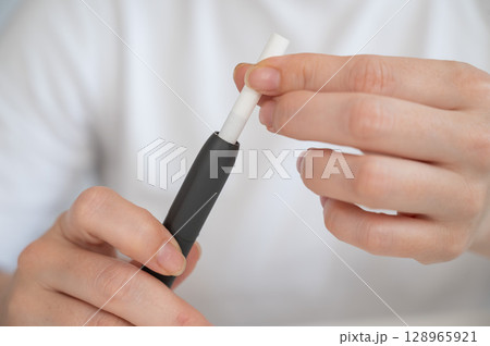 A woman inserts a cigarette stick into a tobacco heating system. Electronic cigarette. 128965921