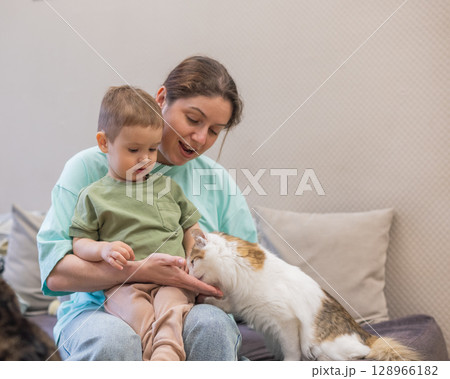 Caucasian woman with her son in a cat cafe.  128966182