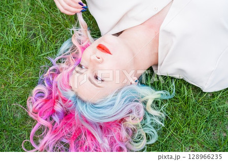 Caucasian woman with colorful hair on green grass. Caucasian woman with colorful hair on green grass. 128966235