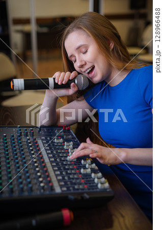 Young woman mixing live sound. Girl recording a song in the studio.  128966488