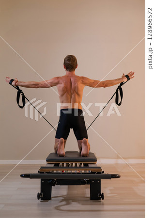 A man doing Pilates on a reformer.  128966572