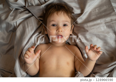 Top view of cute caucasian toddler lying in bed.  128966590