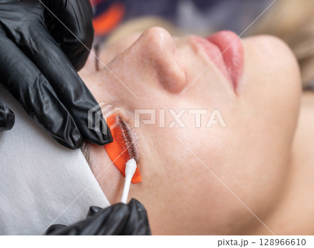 Caucasian woman undergoing eyelash lamination procedure. Caucasian woman undergoing eyelash lamination procedure. 128966610
