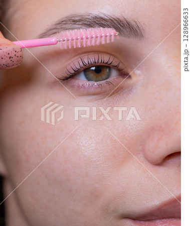 Caucasian woman brushing her eyelashes after lamination.  128966633