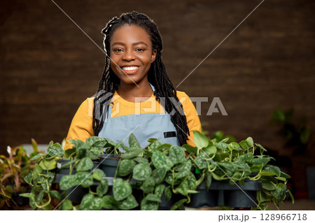 Smiling african american woman with flower pots looking happy Smiling african american woman with flower pots looking happy 128966718