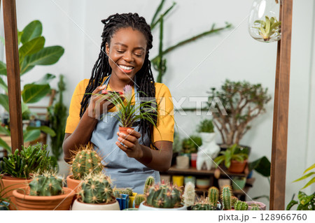 Flower shop assistant cutting flowers and looking contented and happy Flower shop assistant cutting flowers and looking contented and happy 128966760