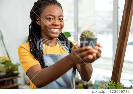 African american cute female flower shop assistant with cactuses 128966783