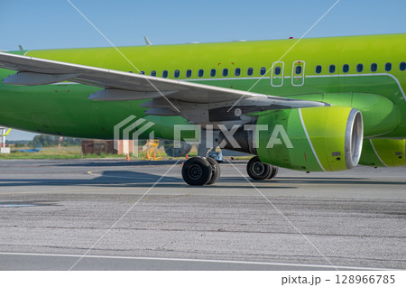 Airplane undergoing repairs in the open air. 128966785