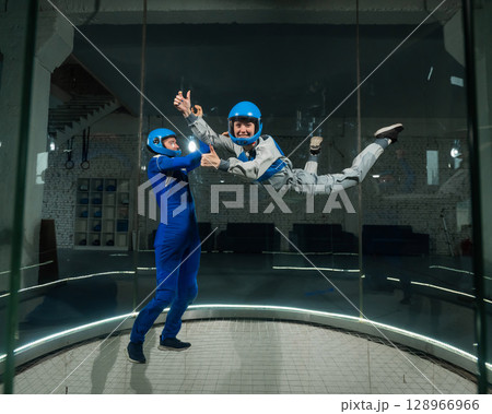 A male instructor teaches a woman how to fly in a wind tunnel. Free fall simulator. A male instructor teaches a woman how to fly in a wind tunnel. Free fall simulator. 128966966