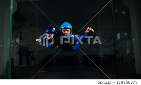 A man teaches a boy to fly in a wind tunnel. Lack of gravity. 128966975