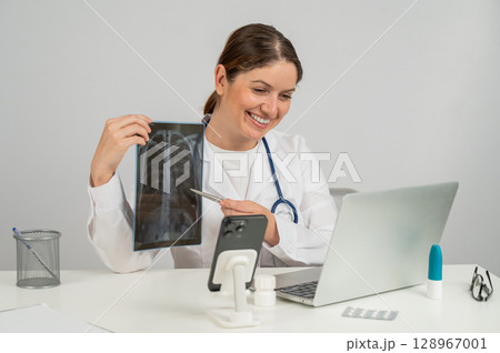 Telemedicine. Caucasian female doctor communicates with patient on laptop and shows x-ray of lungs.  128967001
