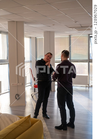 Two Caucasian men talking at work in the office. Two Caucasian men talking at work in the office. 128967029