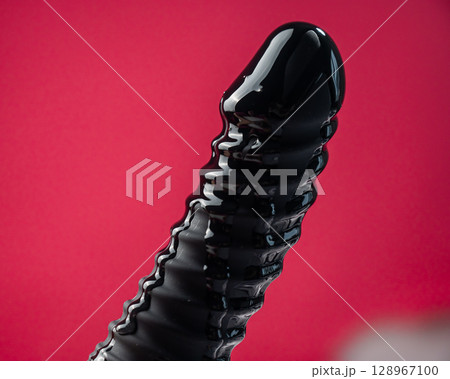 Lube pouring on black dildo on pink background.  128967100