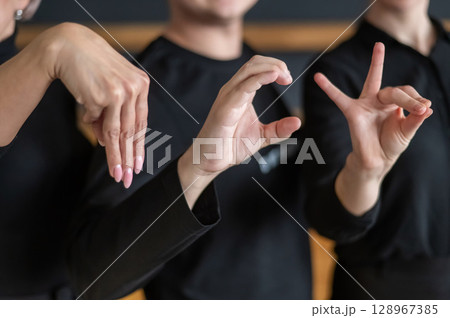 A man and two women demonstrate a phrase in sign language.  128967385