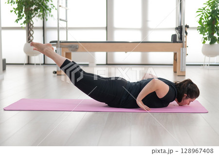 A plump woman does Pilates in a studio. A plump woman does Pilates in a studio. 128967408