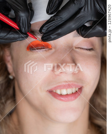 Caucasian woman undergoing eyelash lamination procedure. Caucasian woman undergoing eyelash lamination procedure. 128967420
