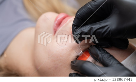 Caucasian woman undergoing eyelash lamination procedure. Caucasian woman undergoing eyelash lamination procedure. 128967445