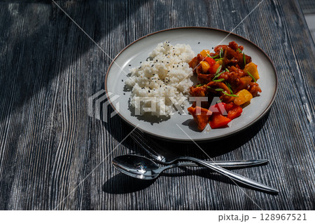 Pork in sweet and sour sauce with boiled rice on a plate. Pork in sweet and sour sauce with boiled rice on a plate. 128967521