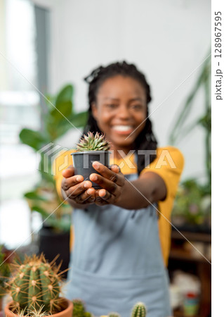 African american cute female flower shop assistant with cactuses 128967595