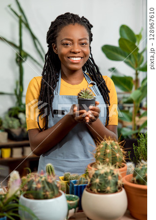 African american cute female flower shop assistant with cactuses African american cute female flower shop assistant with cactuses 128967610