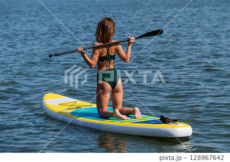 Caucasian woman posing on a SUP board. Summer sport. Caucasian woman posing on a SUP board. Summer sport. 128967642