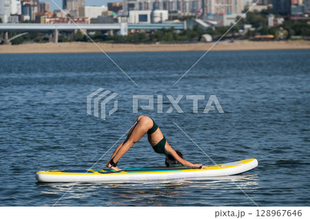 Caucasian woman doing yoga on a SUP board.  128967646