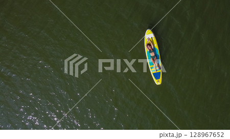 Caucasian woman riding a SUP board on the lake. View from above. Summer sport. Caucasian woman riding a SUP board on the lake. View from above. Summer sport. 128967652