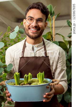 Man in apron holding a flower bed with succulents Man in apron holding a flower bed with succulents 128967695