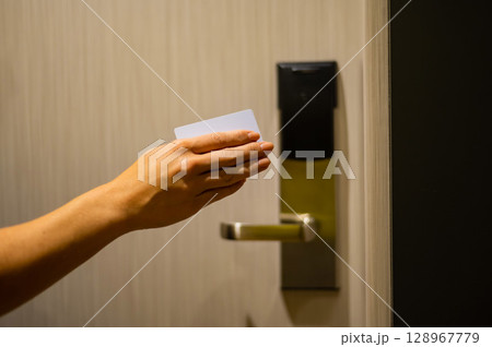 A woman opens an electronic lock with a card and enters a hotel room. A woman opens an electronic lock with a card and enters a hotel room. 128967779