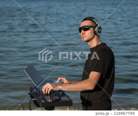Male DJ playing music on the beach.  128967799