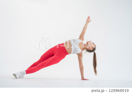 Young woman doing side plank on white background. 128968019