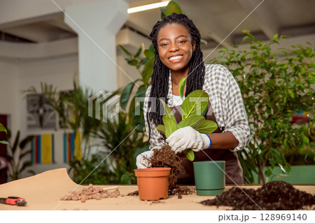 Smiling flower shop assistant planting flowers and feeling good 128969140