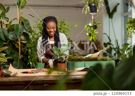 Cute african american florist planting flowers in the flower shop 128969153