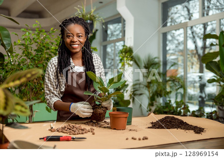 Young female florist working with plants in the flower shop Young female florist working with plants in the flower shop 128969154