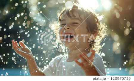 Cheerful little boy joyfully splashing in water with blue background Cheerful little boy joyfully splashing in water with blue background 128970739
