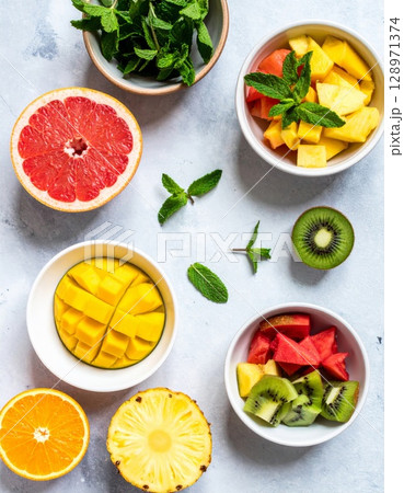 Vibrant Fresh Fruit Still Life Featuring Citrus Slices in White Bowls on Grey Table Vibrant Fresh Fruit Still Life Featuring Citrus Slices in White Bowls on Grey Table 128971374