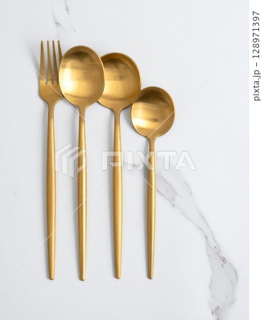 Golden Fork and Spoons on Marble Surface in a Clean Minimalist Kitchen Setting Golden Fork and Spoons on Marble Surface in a Clean Minimalist Kitchen Setting 128971397