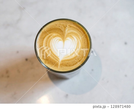 Overhead of Latte Art Heart in Glass Cup on Marble Tabletop at Cafe 128971480