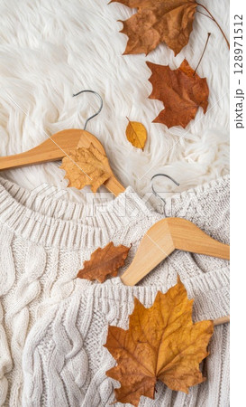 Ivory Knit Sweaters with Fall Leaves on a Plush White Textile Background 128971512