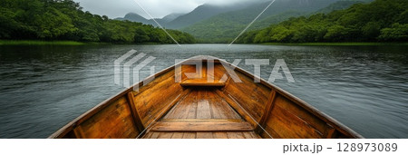 Solitary boat enters a tranquil forested bay, its bow pointing to the misty horizon under soft morning light and tall trees. Solitary boat enters a tranquil forested bay, its bow pointing to the misty horizon under soft morning light and tall trees. 128973089
