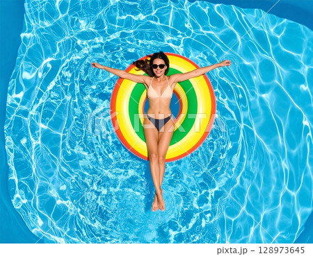 プールで浮き輪に乗ってリラックスする女性のイラスト 128973645