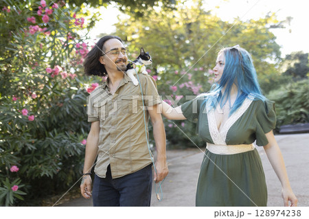 Couple walking with kitten on leash in park Couple walking with kitten on leash in park 128974238