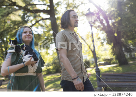 Couple walking in park with cat on leash 128974240