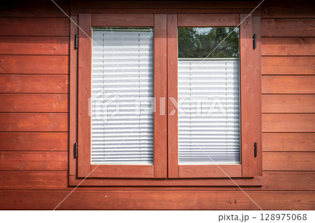 Closed Wooden Window with White Blinds on Red Cabin Wall in Bright Daylight 128975068