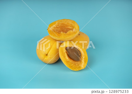 Juicy apricots with visible seed placed on vibrant blue background. 128975233