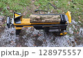 Log splitter machine splitting wood logs on snowy ground 128975557