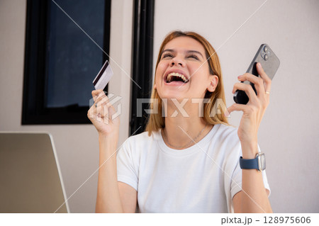 Happy young caucasian woman holding credit card or debit card paying with shopping online. 128975606